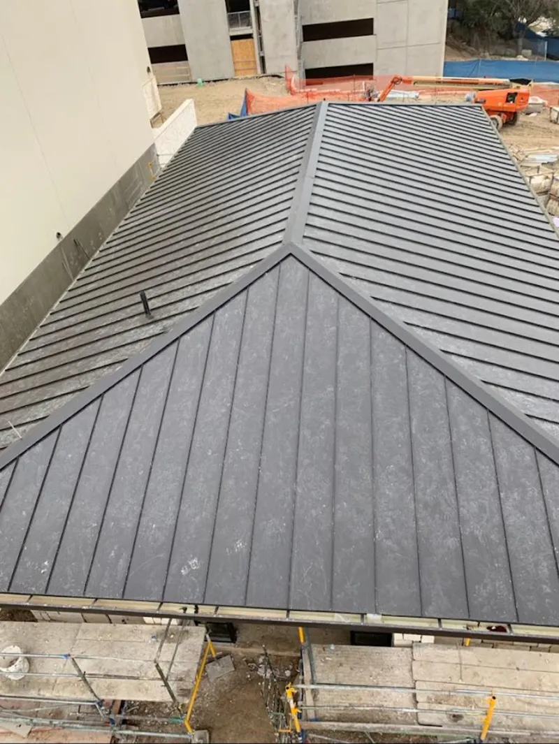 Commercial metal roof construction with crane equipment in Suffield